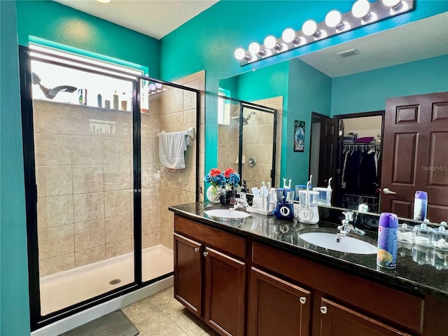 full bath featuring a stall shower, a sink, a walk in closet, and tile patterned floors