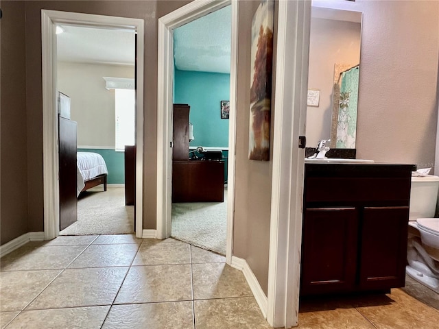 hallway with a sink, baseboards, and light tile patterned floors