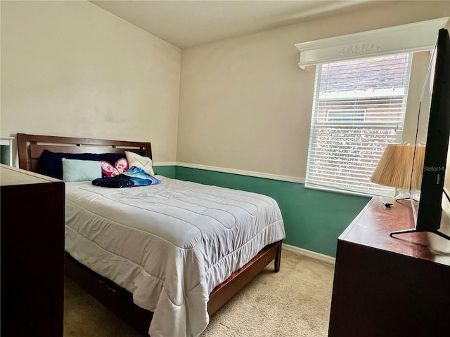 bedroom with baseboards and light colored carpet