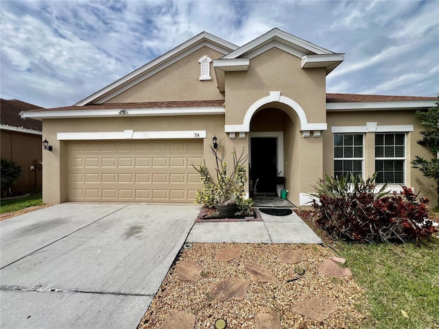 view of front facade with a garage, driveway, and stucco siding