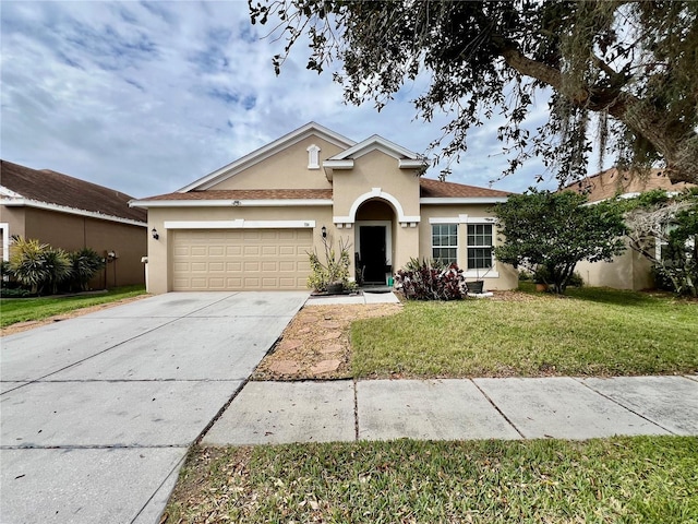 view of front of house featuring driveway, a front lawn, an attached garage, and stucco siding