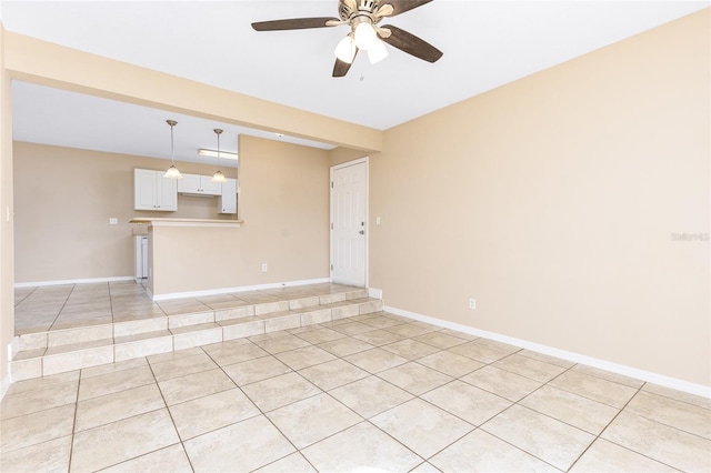 spare room featuring light tile patterned floors, ceiling fan, and baseboards