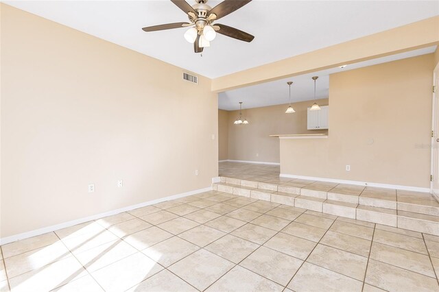 empty room featuring light tile patterned flooring, visible vents, baseboards, and ceiling fan with notable chandelier