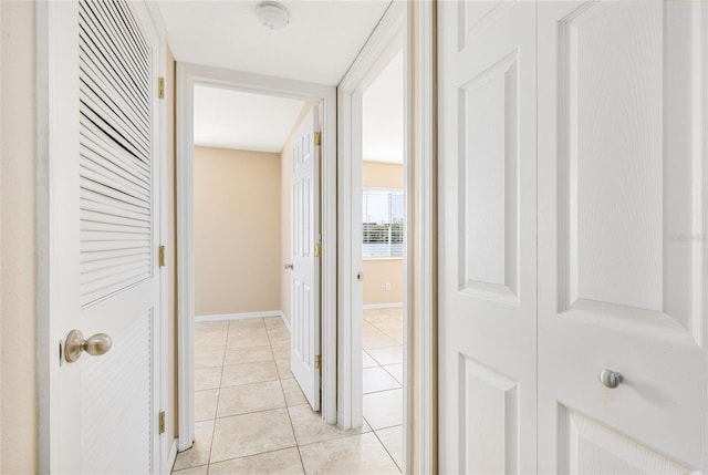 hall featuring baseboards and light tile patterned flooring