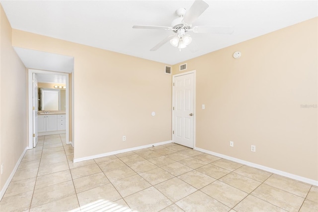 spare room with light tile patterned flooring, ceiling fan, visible vents, and baseboards