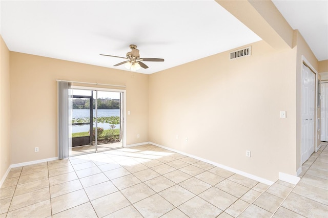 empty room featuring light tile patterned floors, ceiling fan, visible vents, and baseboards