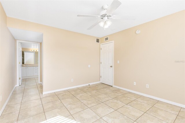 empty room featuring light tile patterned floors, baseboards, ceiling fan, and visible vents
