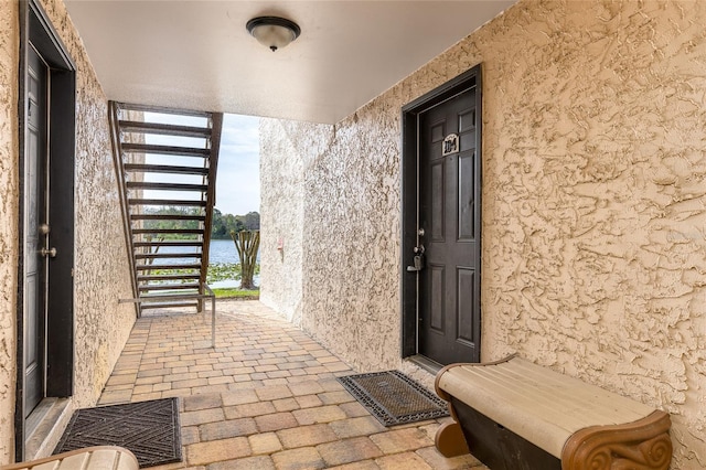 entrance to property with a water view and stucco siding