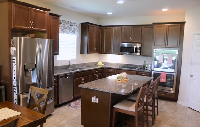 4110 Arlington Ridge Blvd, Leesburg, FL 34748 - kitchen featuring appliances with stainless steel finishes, a sink, a kitchen island, dark stone counters, and dark brown cabinets