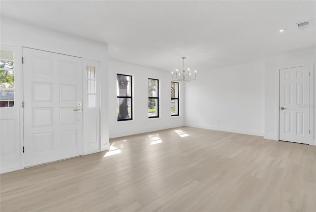 entryway featuring a wealth of natural light, visible vents, a notable chandelier, and light wood finished floors