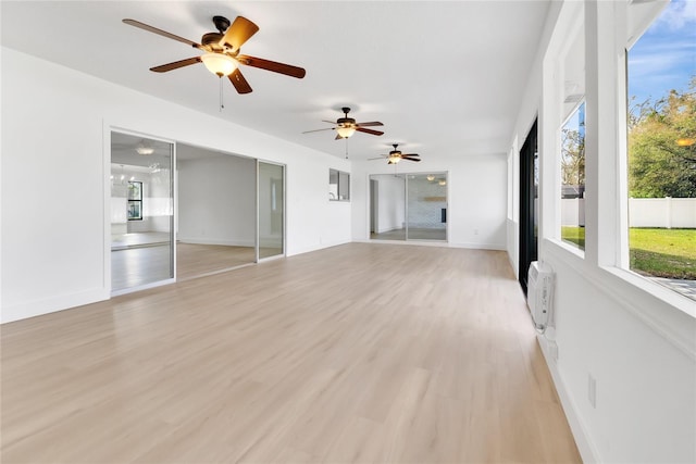 empty room featuring light wood finished floors, baseboards, and a wall mounted air conditioner