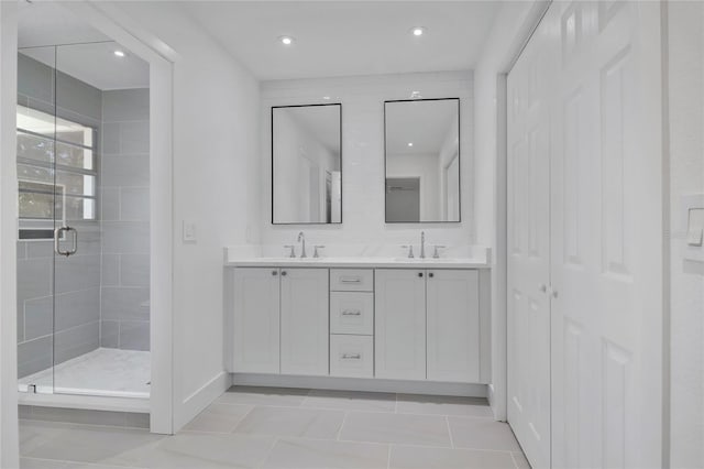 full bathroom featuring double vanity, baseboards, tile patterned flooring, a shower stall, and a sink