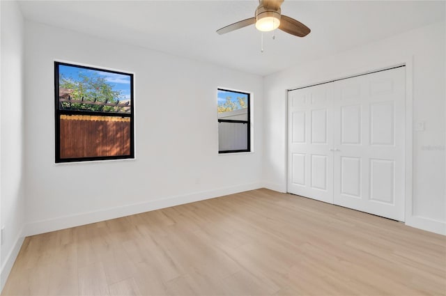 unfurnished bedroom with light wood-style flooring, baseboards, ceiling fan, and a closet