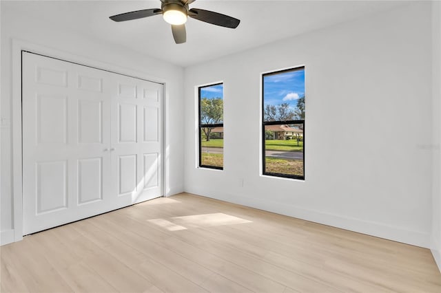 unfurnished bedroom with baseboards, a closet, a ceiling fan, and light wood-style floors