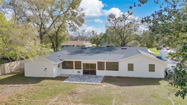 rear view of property featuring fence, a lawn, and a patio