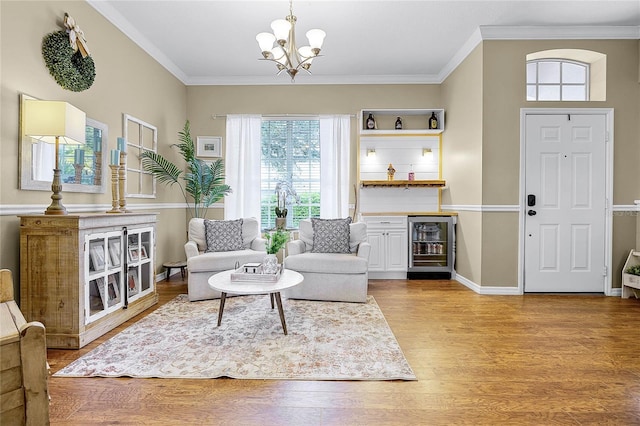 living area featuring ornamental molding, wine cooler, a notable chandelier, and light wood finished floors