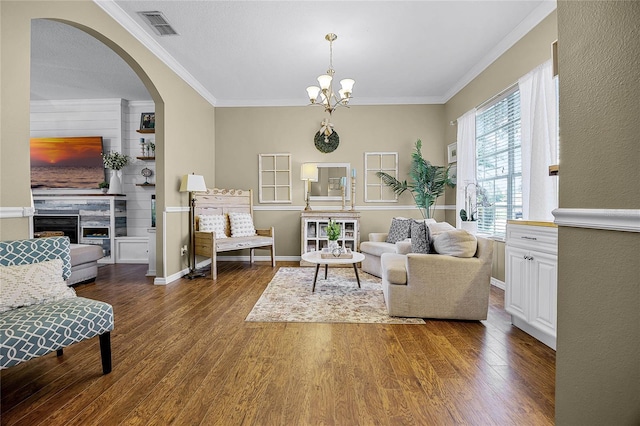 sitting room with ornamental molding, a tiled fireplace, wood finished floors, and visible vents