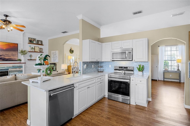 kitchen with arched walkways, appliances with stainless steel finishes, a sink, and visible vents