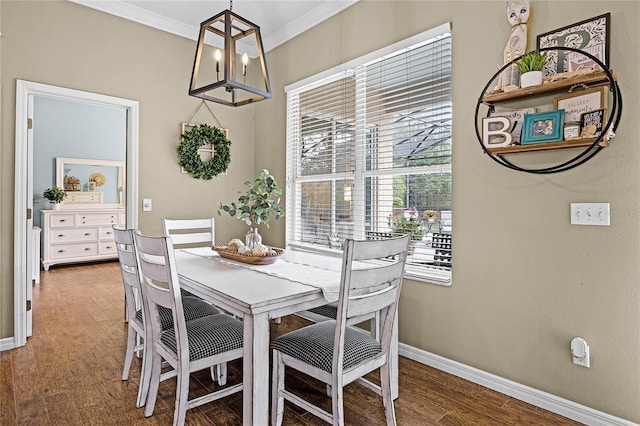 dining room with an inviting chandelier, baseboards, crown molding, and wood finished floors