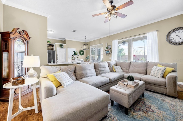 living room featuring a ceiling fan, crown molding, visible vents, and wood finished floors