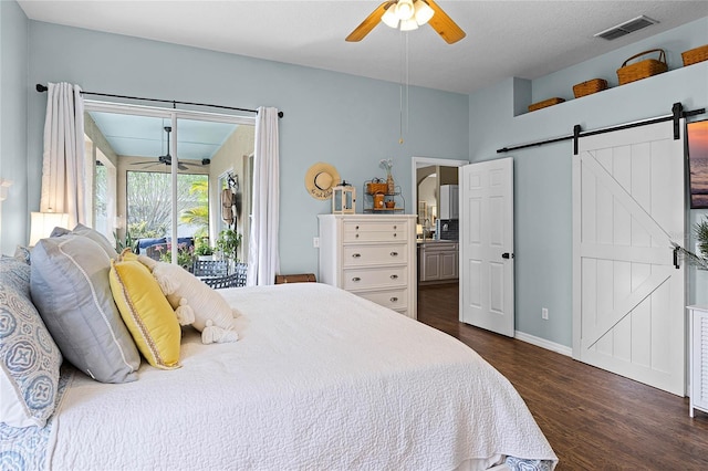 bedroom with access to exterior, dark wood-style floors, visible vents, a barn door, and a ceiling fan