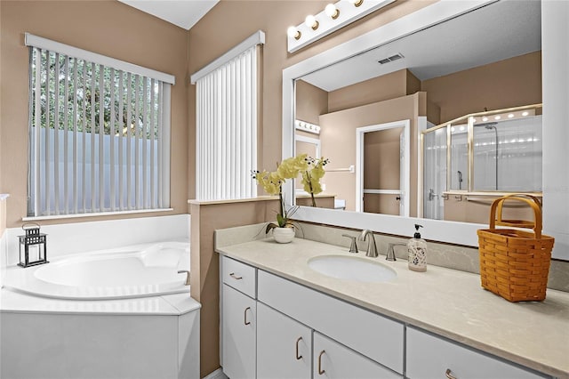 bathroom with a stall shower, visible vents, a bath, and vanity