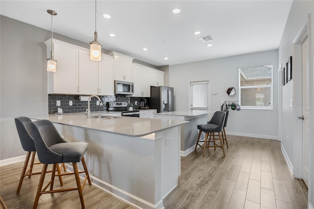 kitchen featuring tasteful backsplash, light wood-style flooring, a breakfast bar area, stainless steel appliances, and a sink