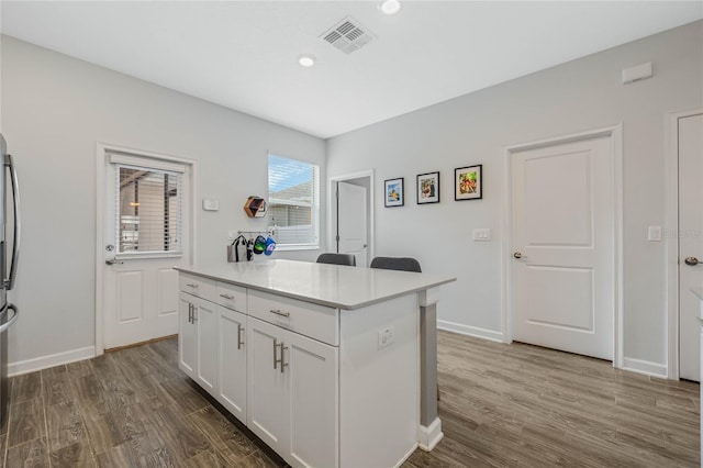 kitchen featuring dark wood-type flooring, a center island, visible vents, and white cabinets