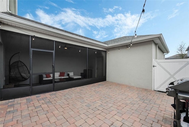 view of patio featuring grilling area, a gate, and a sunroom