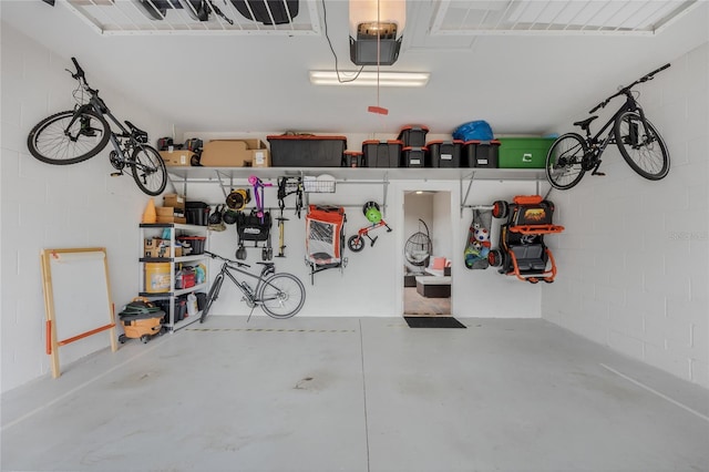 garage featuring bike storage, concrete block wall, and a garage door opener