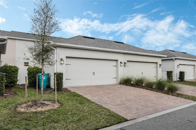 view of front of house with a garage, decorative driveway, a shingled roof, and stucco siding