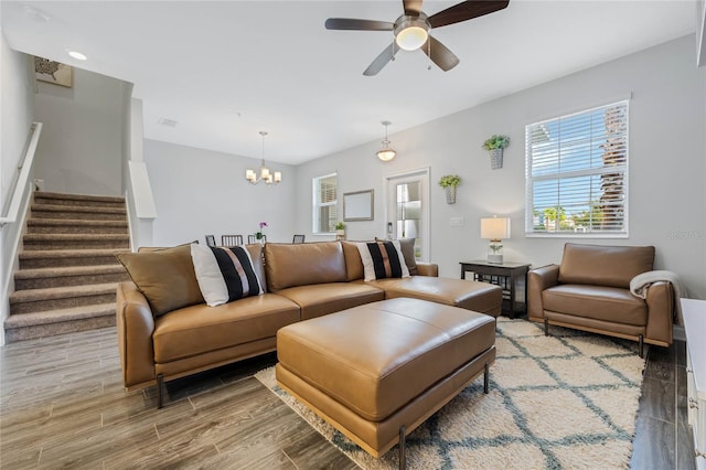 living room featuring stairs, ceiling fan with notable chandelier, wood finished floors, and a wealth of natural light