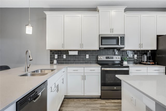 kitchen featuring light wood-style floors, decorative backsplash, stainless steel appliances, and a sink