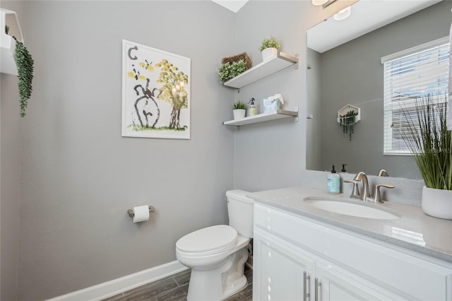 bathroom featuring toilet, baseboards, wood finished floors, and vanity