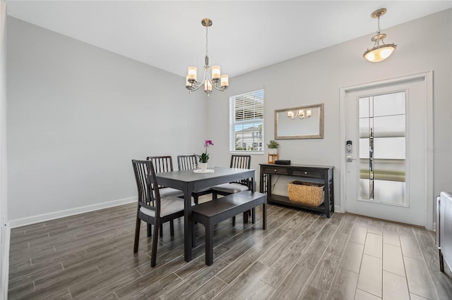 dining area with baseboards, wood finished floors, and an inviting chandelier