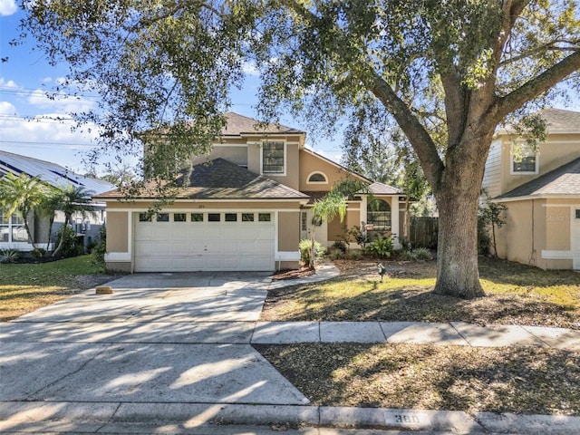 traditional-style house featuring concrete driveway, an attached garage, and stucco siding