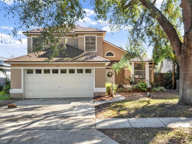 view of front facade with a garage, driveway, fence, and stucco siding