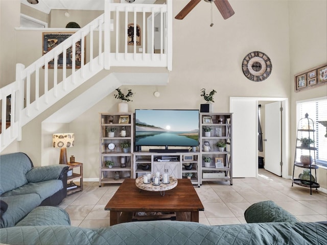 living area featuring a ceiling fan, stairway, a towering ceiling, and tile patterned floors