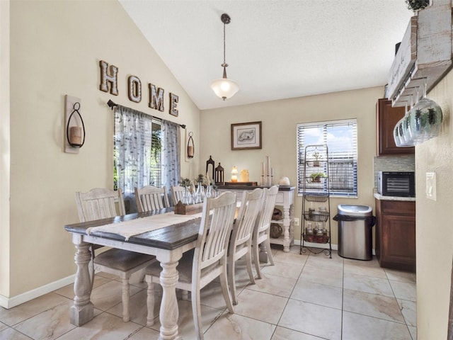 dining room featuring lofted ceiling, baseboards, a textured ceiling, and light tile patterned flooring