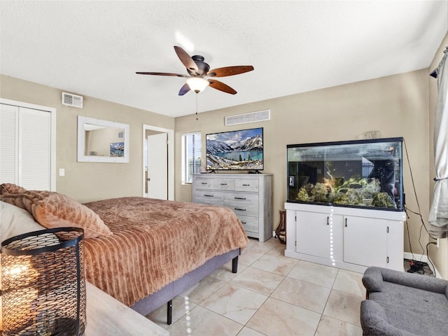 bedroom with a ceiling fan, a closet, visible vents, and a textured ceiling