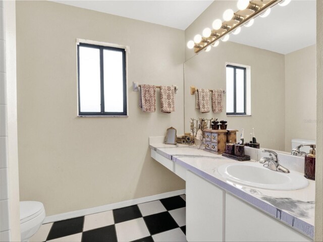 bathroom with toilet, vanity, baseboards, and tile patterned floors