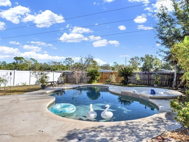 view of swimming pool featuring a pool with connected hot tub, a patio area, and a fenced backyard