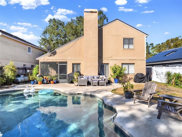 rear view of property featuring a chimney, fence, outdoor lounge area, and a patio