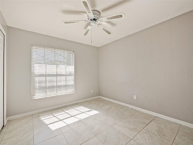 spare room with baseboards, a ceiling fan, and light tile patterned flooring