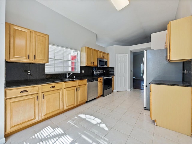 kitchen with light tile patterned floors, stainless steel appliances, dark countertops, and backsplash