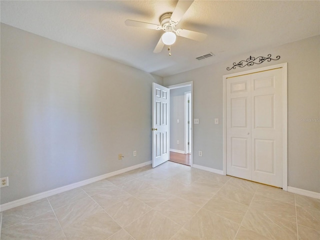 unfurnished bedroom with a closet, visible vents, ceiling fan, and baseboards