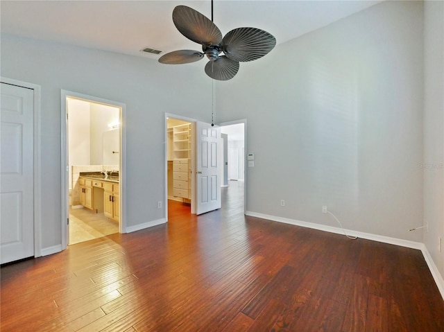 unfurnished bedroom featuring wood finished floors, visible vents, baseboards, a spacious closet, and a closet