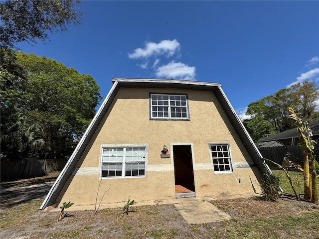 rear view of property with fence and stucco siding