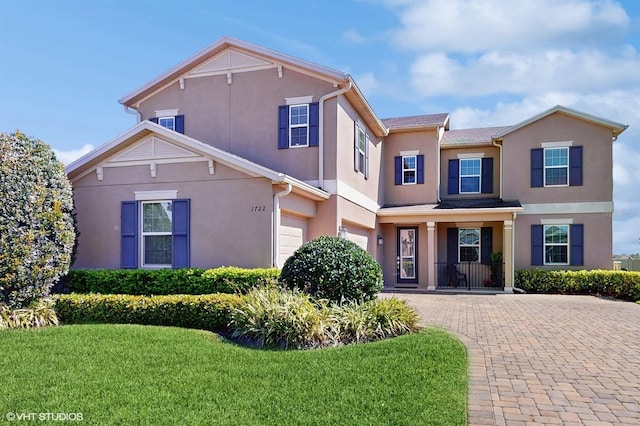 view of front of house featuring a front yard, decorative driveway, and stucco siding