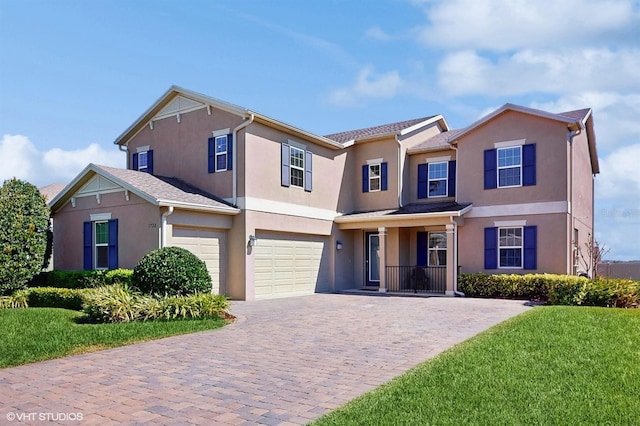 traditional home featuring a front lawn, decorative driveway, an attached garage, and stucco siding